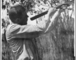 Phil Eppley shooting native crossbow in 1944, in Szemao or Mengsa, during WWII. Note native stockade of bamboo in the background. 