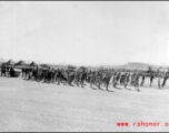 Laborers pull roller at Liuzhou during WWI, in 1945. GI tents can be seen in the distance.
