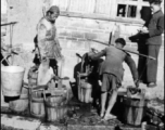 Town people in China get water in wooden buckets and shoulder poles during WWII.