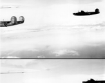 B-24 bombers in flight over water, with land in the background. Note the different paint scheme on the two planes, and shark teeth on the right plane.   Tail number 440780 on the left plane should make this "Red Hot Riding Hood," with the 374th Bombardment Squadron, 308th Bombardment Group.