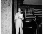 A GI reads from a script during a variety show, while the band Jive-o-Lieps prepares to play music in the CBI during WWII. 54th Air Service Group.