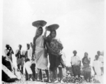 Women carry baskets of crushed stone on their heads.  Scenes in India witnessed by American GIs during WWII. For many Americans of that era, with their limited experience traveling, the everyday sights and sounds overseas were new, intriguing, and photo worthy.