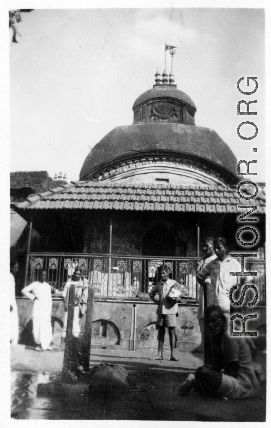 People in front of temple-like building in Burma or India, possibly looking at wrapped body.  Near the 797th Engineer Forestry Company.  During WWII.