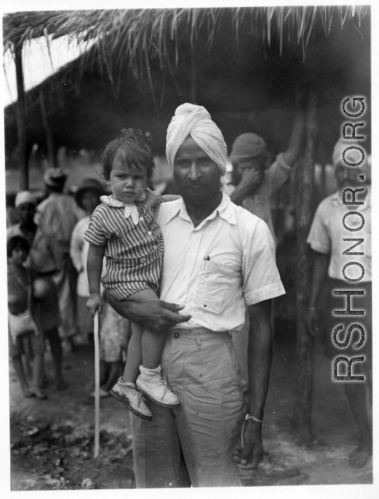 Man holds child in Burma or India.  Near the 797th Engineer Forestry Company.  During WWII.