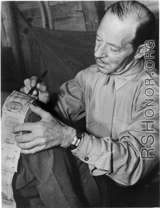 A VIP visitor signs a short-snorter on the back of an American GI, during WWII.  An American in the CBI.