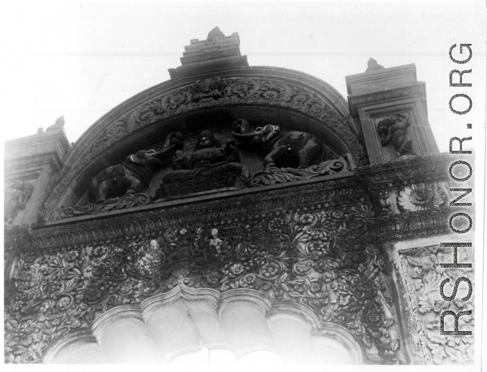 Ornate carved arch doorway, likely as part of a temple complex.  Scenes in India witnessed by American GIs during WWII. For many Americans of that era, with their limited experience traveling, the everyday sights and sounds overseas were new, intriguing, and photo worthy.