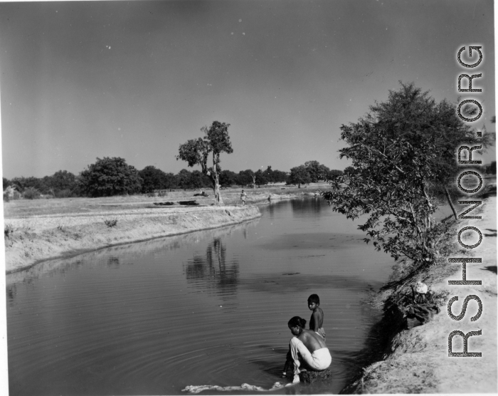 Woman washing cloth in river or canal.  Scenes in India witnessed by American GIs during WWII. For many Americans of that era, with their limited experience traveling, the everyday sights and sounds overseas were new, intriguing, and photo worthy.