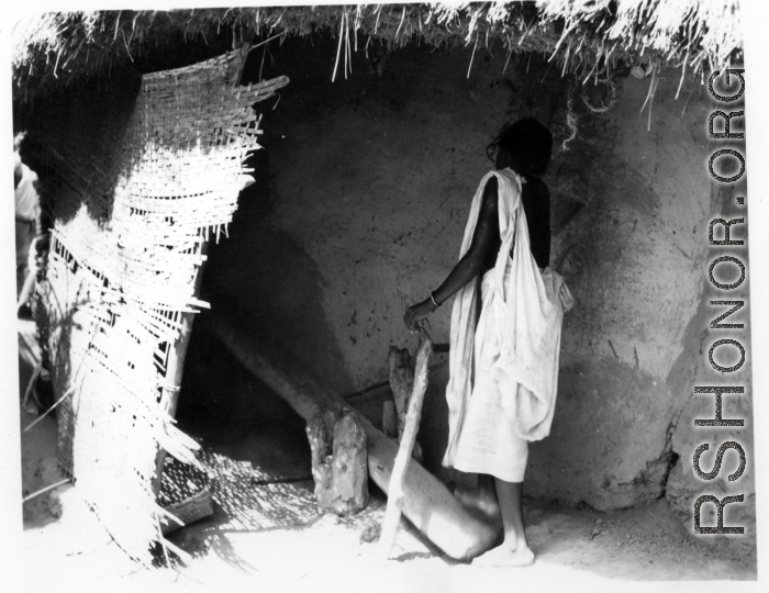 A woman uses a "dhenki" foot lever for dehusking grain. India.  Scenes in India witnessed by American GIs during WWII. For many Americans of that era, with their limited experience traveling, the everyday sights and sounds overseas were new, intriguing, and photo worthy.