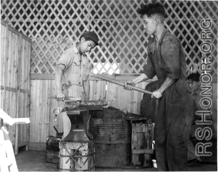 Iron smiths in China forge a large steel rod during WWII.