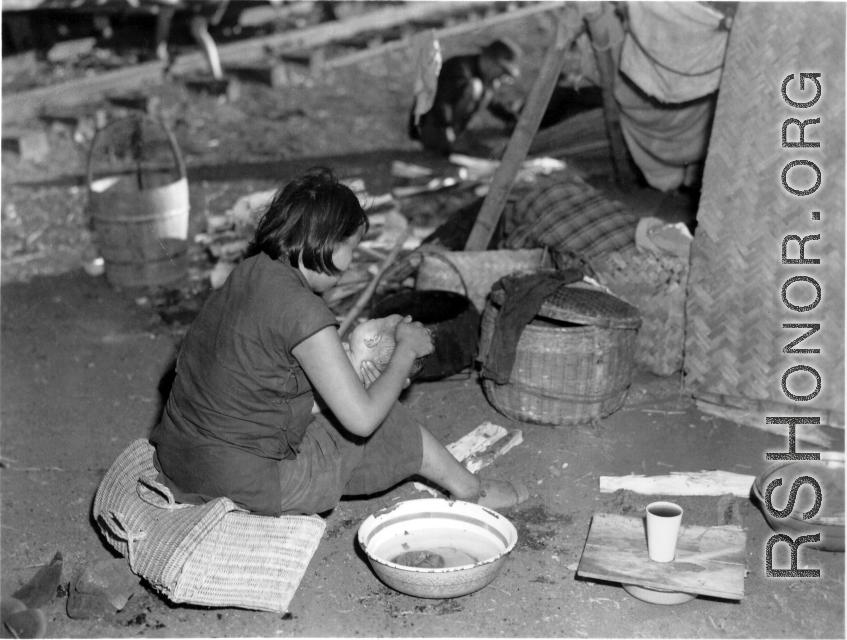 In the midst of calamity, a refugee mother tenderly washes her baby next to the train at the Liuzhou railway station in the fall of 1944.