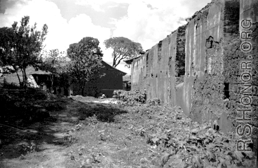 Adobe back wall of a large building. Local scenes and local people in Yunnan province, China, most likely around the Luliang air base area.