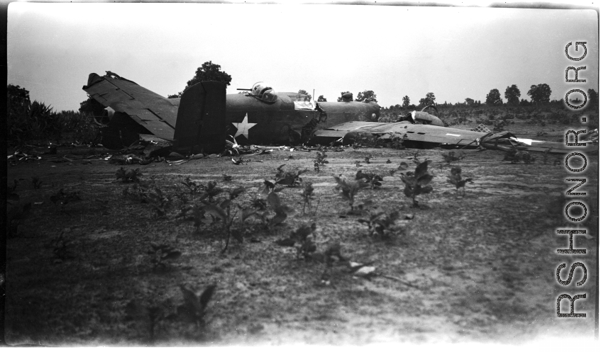 Wrecked B-25 Mitchell bomber on the ground in the CBI. The wreck was apparently at an air base, and probably on take-off, as the craft is sprayed with fire-retardant foam, and bombs are scattered about the wreck site. During WWII.