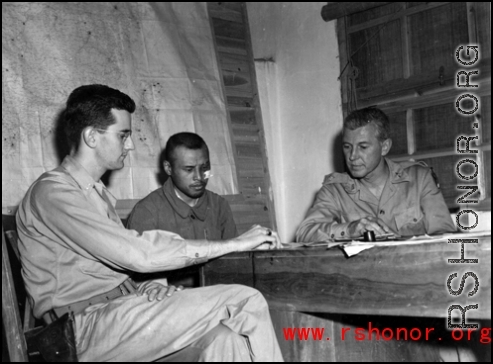 Officers--including possibly a Chinese translator--meet at a base in China during WWII.