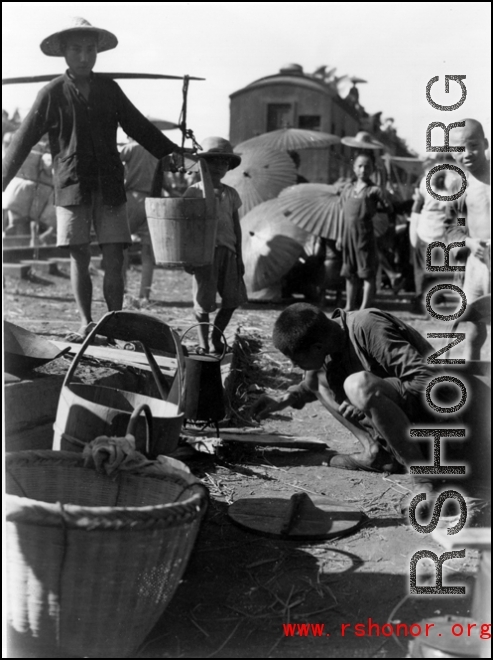 Chinese refuges tends a cooking fire to boil water next to the train tracks in Liuzhou during WWII, in the fall of 1944, as the Japanese advanced during the Ichigo campaign.