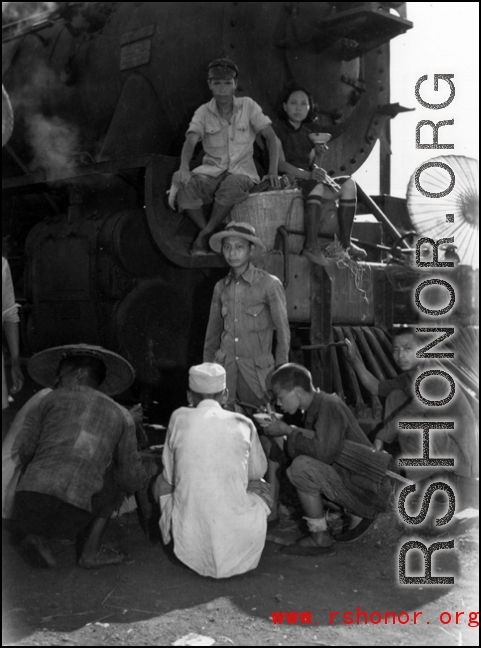 Chinese refugees take a meal in front of the train engine in Liuzhou during WWII, in the fall of 1944, as the Japanese advanced during the Ichigo campaign.