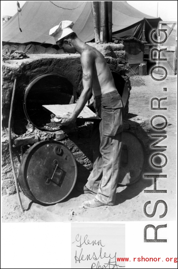 *******A young GI chef, cigarette in mouth, attends to his simple oven full of baked goods. In the CBI during WWII.  Photo from Glenn Hensley.