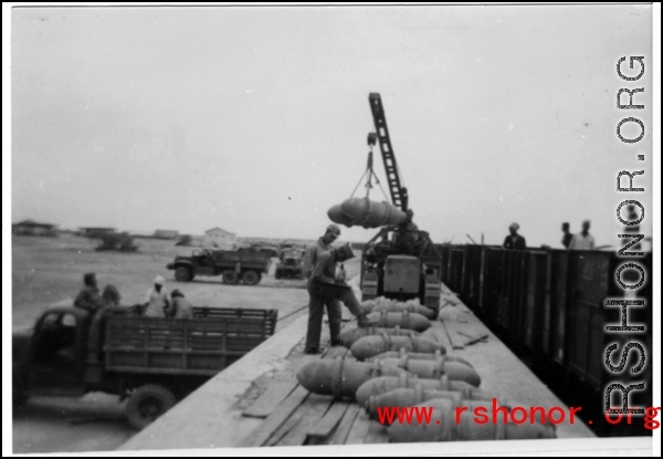 GIs moving aerial bombs between trucks and train in the CBI during WWII.