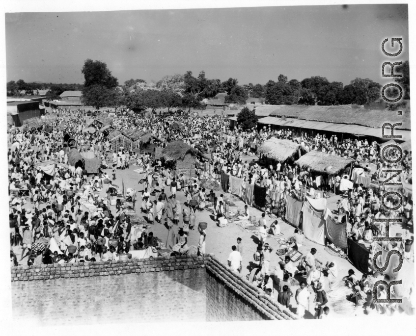 Expansive and busy market crowded with people.  Scenes in India witnessed by American GIs during WWII. For many Americans of that era, with their limited experience traveling, the everyday sights and sounds overseas were new, intriguing, and photo worthy.