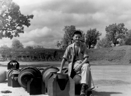 An American at a base in China sitting on bomb tail fins.  (Image from the collection of Eugene Wozniak)