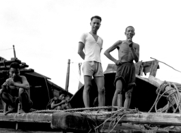 Chinese men on a wooden structure give a curious smile for the photographer, China.  From the collection of Wozniak, combat photographer for the 491st Bomb Squadron, in the CBI.