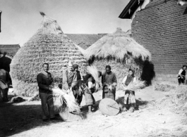 American GIs and people in a local village in Yunnan province, China, threshing grain by striking the rice straw against grinding stones.  From the collection of Eugene T. Wozniak.