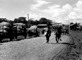 Carts, people, and animals along a road near an American base in Yunnan during WWII.