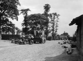 Local people in a village in Yunnan province, China loading or unloading a truck, with lumber and/or farm goods and livestock. During WWII.