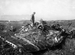 A GI examines the wing of a crashed aircraft in the CBI during WWII.