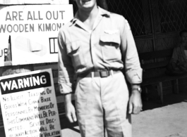 A GI stands before signs on a base in China during WWII.