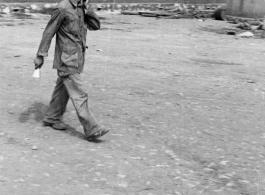 A Chinese staff person walks across an open area of a hostel in Yunnan province, China, most likely around the Luliang air base area.