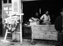 Butcher shop with fresh meat hung to carve in China during WWII.