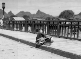 A tired elderly refugee resting on a bridge in Guilin in summer/fall 1944, in front of the Japanese advance.  From the collection of Hal Geer.