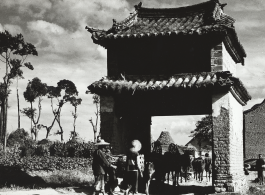 Farm folk go through a gate-like structure near Kunming, in Yunnan province. During WWII.