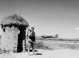 An American C-47 takes off behind a Chinese base guard in SW China during WWII.