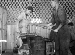 Iron smiths in China forge a large steel rod during WWII.