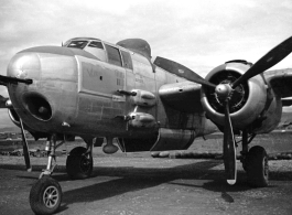 B-25 Mitchell in Yunnan, China, during WWII, with a row of bombs laid out on the ground behind, and bomb  bay doors open.