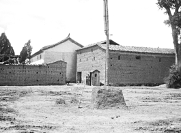 Some large, possibly official, buildings near or on an American air base in Yunnan, China, during WWII. Note the small guard shack at the opening between the structures.
