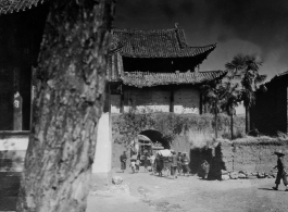 A village gate, with a temple to left with “太平乐事” written above door. During WWII.