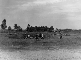 Personnel collect up some errant bombs that are strangely scattered in the grass near the base. During WWII.