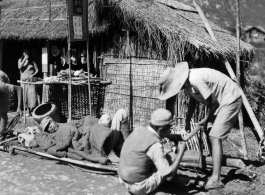 Stretcher bearers take a break in Guangxi province, either Guilin or Liuzhou area, probably during the evacuation of fall 1944. The white paper posted on the store sign says basically, "Everything for sale, including building, animals, possessions."