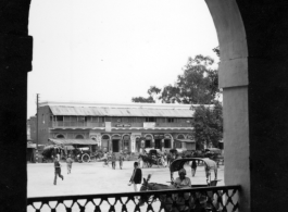 View out through archway to street and shops.  Scenes in India witnessed by American GIs during WWII. For many Americans of that era, with their limited experience traveling, the everyday sights and sounds overseas were new, intriguing, and photo worthy.