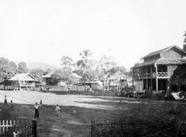 Fence village in Burma. A small crude stage is built in front of the house on the far right.  Near the 797th Engineer Forestry Company.  During WWII.