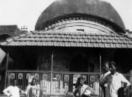 People in front of temple-like building in Burma or India, possibly looking at wrapped body.  Near the 797th Engineer Forestry Company.  During WWII.