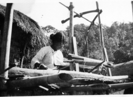 Local people in Burma near the 797th Engineer Forestry Company--A woman weaves on a loom in Burma.  During WWII.