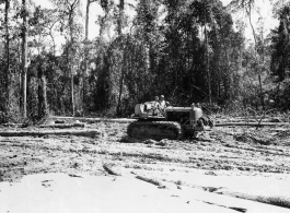 Bulldozer pulling log through mud in Burma.  797th Engineer Forestry Company in Burma.  During WWII.