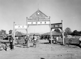 A Chinese settlement in Burma, with Nationalist insignia on gate archway. This is likely to be a settlement highly reliant on trade and commerce as its niche.  Near the 797th Engineer Forestry Company.  During WWII.  "华侨新村“  “祖国之光”