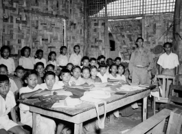 Local people in Burma near the 797th Engineer Forestry Company--GI visits a local school (very likely a missionary school, given the materials in the classroom and the clothing the kids are wearing) in Burma.  During WWII.