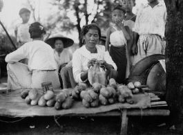 A woman sells cucumbers or something similar in Burma.  Local people in Burma near the 797th Engineer Forestry Company.  During WWII.