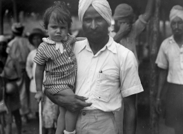 Man holds child in Burma or India.  Near the 797th Engineer Forestry Company.  During WWII.