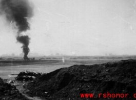 An American airplane burning in the distance after a Japanese air raid. In China, during WWII.